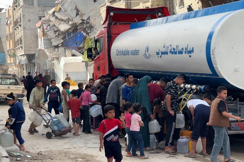 أطفال ونساء ورجال يقومون بملء أوعيتهم من المياه.